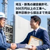 建設現場を背景に握手する作業服の建設業者と建設業許可証を持つスーツの行政書士。埼玉・群馬の建設業許可申請代行（丸投げサポート）のイメージ画像。