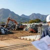 群馬県のスクラップヤード（再生資源物屋外保管事業場）にて、行政書士と事業者が10月施行の条例に向けた許可申請用の図面や設備改修の打ち合わせをしている様子